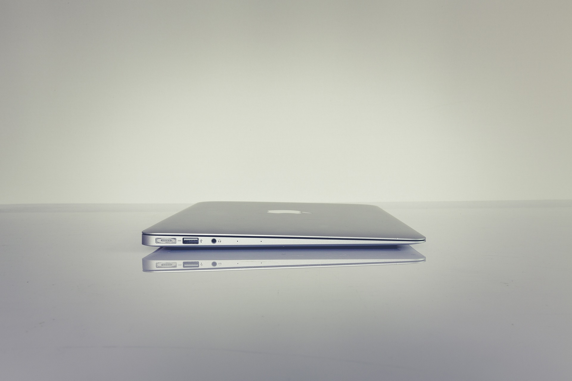 A closed MacBook lies on a grey surface.
